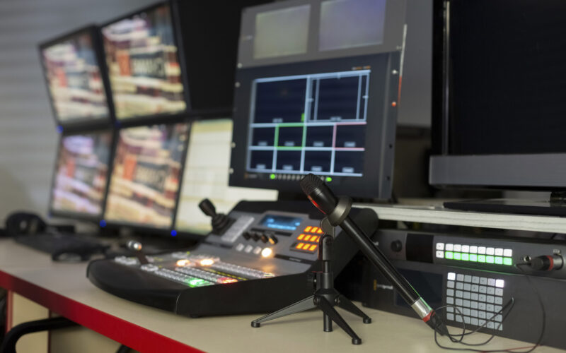 Television director's office with remote control and microphone, monitors, sensors, copy space