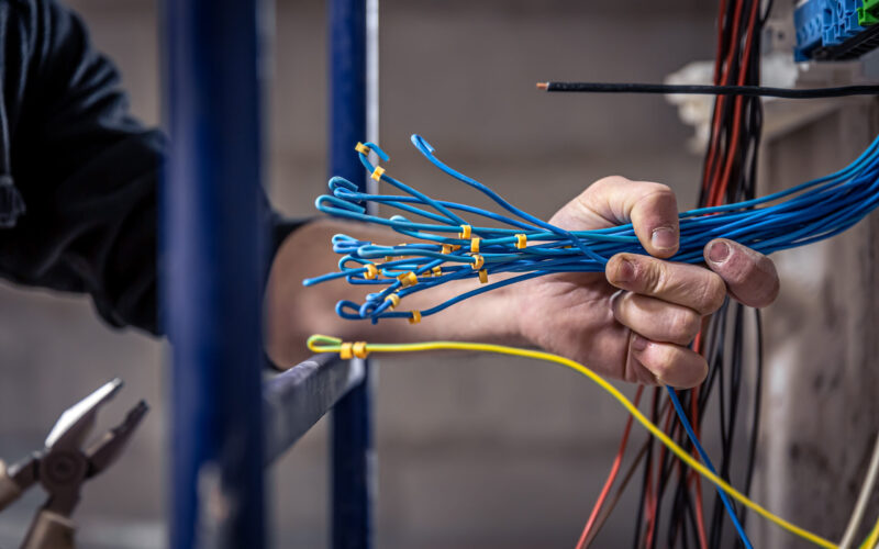 A construction electrician cuts a voltage cable during a repair, close up.
